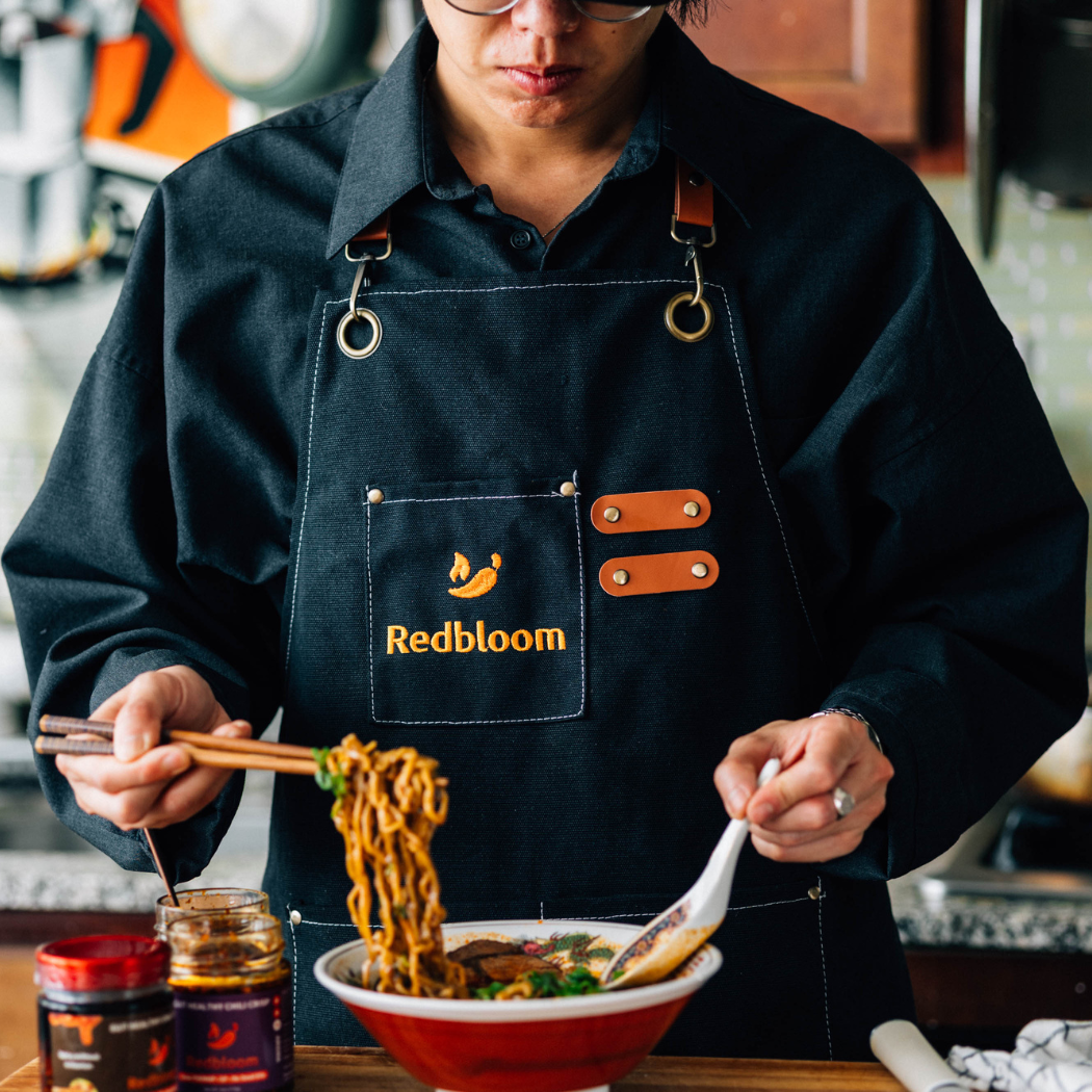 Person wearing a 'Redbloom' apron, preparing food in a kitchen.
